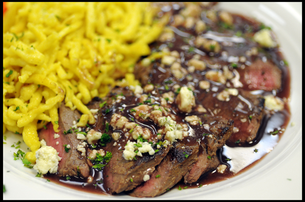 Sliced Beef with a Red Wine Reduction topped with Cabozola Cheese crumbles and served with Spätzle